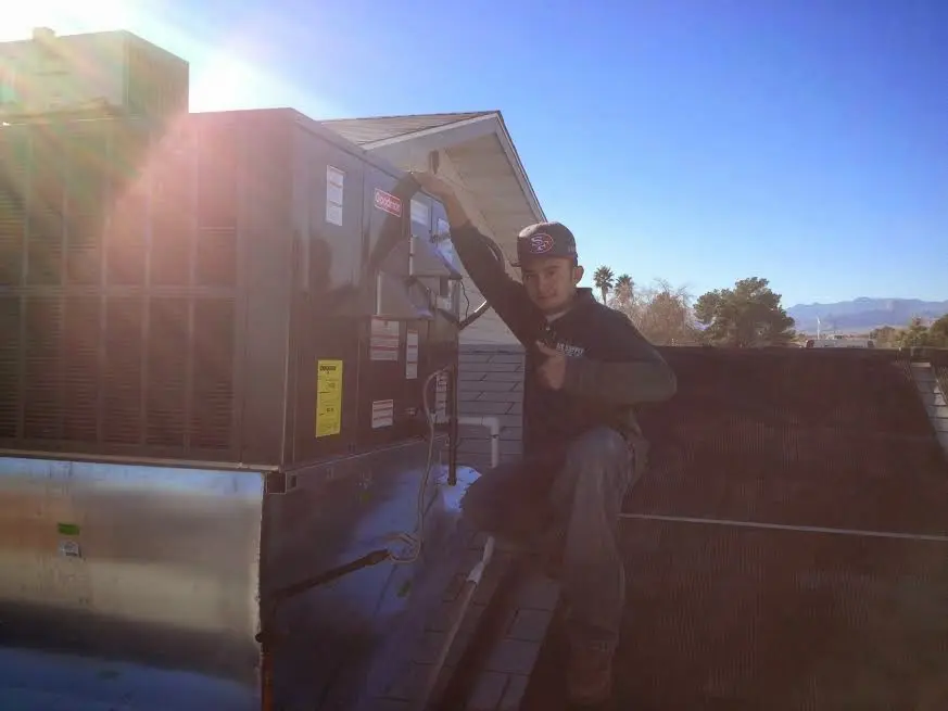 HVAC technician performing Air Duct Repair on a rooftop unit in Carrboro