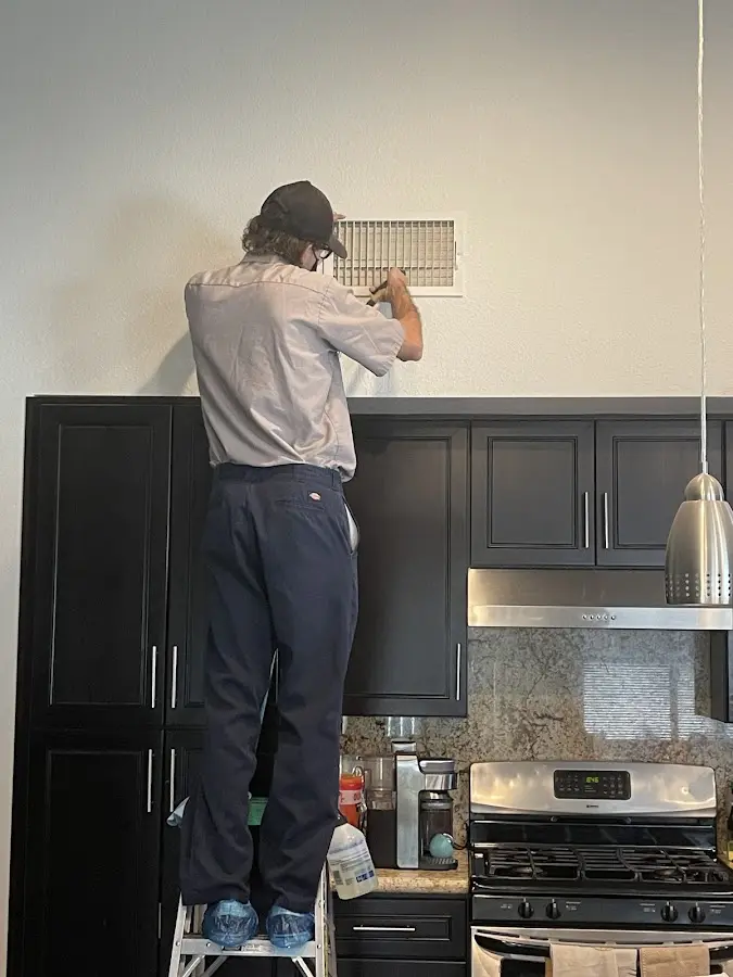 Technician inspecting an air vent during HVAC service in Carrboro